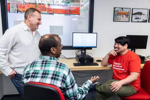 Three men gathered round a computer