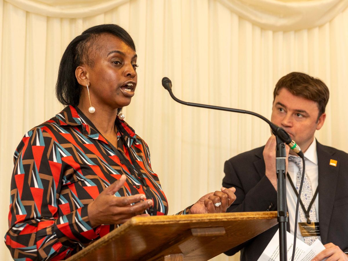 Joan, a Crisis Expert by Experience, standing at a lectern delivering a speech